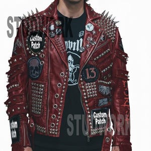 May include: A burgundy leather jacket with silver studs and spikes. The jacket features multiple patches, including a skull and the text "Custom Patch". The person is wearing a black t-shirt with a graphic print.