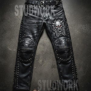 May include: Black leather pants with silver studs and a skull patch. The pants have knee pads and a studded belt. The text "STUDWORK" is visible on the pants.