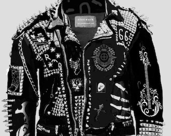 Pode incluir: Uma jaqueta de couro preta com tachas e espinhos prateados. A jaqueta tem vários patches e enfeites, incluindo uma caveira, uma guitarra e o número 66. A jaqueta tem um zíper preto e um cinto preto.