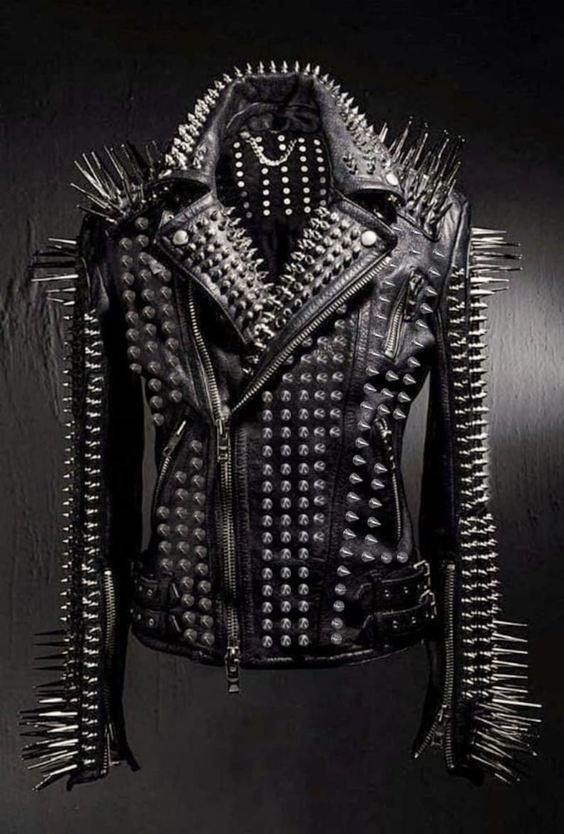 May include: Black leather jacket heavily embellished with silver spikes and studs. The jacket features a classic biker style with a notched collar, asymmetrical zipper, and multiple pockets. The shoulders and sleeves are adorned with long, sharp spikes.