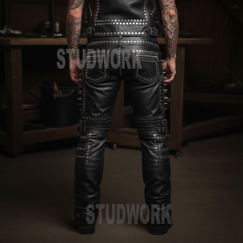 May include: Black leather trousers and vest set with silver stud accents. The trousers feature multiple pockets, zips, and buckle details. The vest is sleeveless and also studded. The word "STUDWORK" is printed on the trousers.
