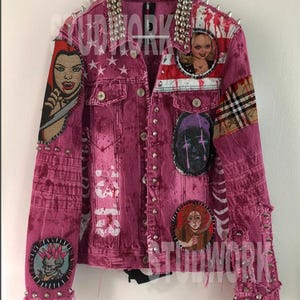 May include: A magenta denim jacket with silver stud and spike embellishments. Patches with horror-themed imagery are sewn on the jacket. The collar is heavily studded. The jacket has a distressed look.