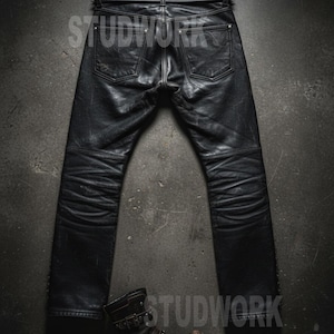 May include: Black leather pants with a matching belt featuring silver studs. The pants have a classic five-pocket design and are paired with a brown leather boot with multiple buckles. The word "STUDWORK" is printed on the image.