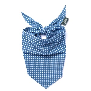 May include: Blue and white gingham dog bandana with a knotted top. The bandana is made of a soft fabric and has a tag attached. The classic pattern is a timeless design for pets.