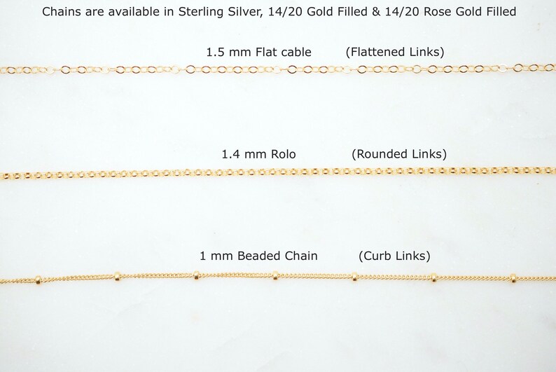 May include: Three gold chains with different link styles and sizes. The top chain is 1.5 mm flat cable with flattened links. The middle chain is 1.4 mm rolo with rounded links. The bottom chain is 1 mm beaded chain with curb links. Chains are available in sterling silver, 14/20 gold filled, and 14/20 rose gold filled.