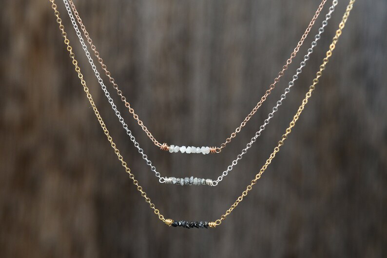 Puede incluir: Tres delicados collares con cadenas de diferentes colores y peque&ntilde;os detalles de diamantes en bruto.