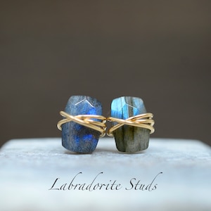 May include: A pair of labradorite stud earrings with gold wire wrapping. The stones are a deep blue with iridescent flashes of color.  Labradorite Studs.