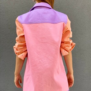 Puede incluir: Una chaqueta vaquera de color rosa, morado y melocot&oacute;n con cierre de botones y mangas largas.