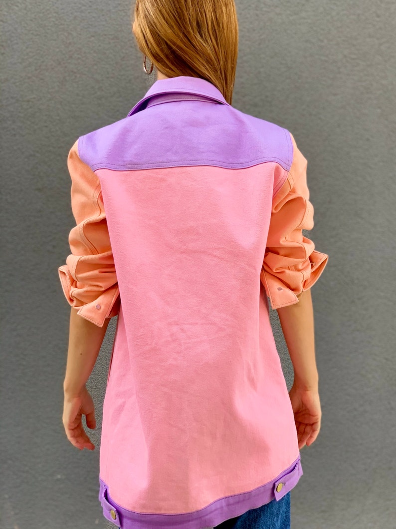 Puede incluir: Una chaqueta vaquera de color rosa, morado y melocot&oacute;n con cierre de botones y mangas largas.