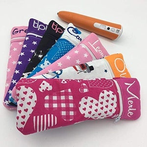 Könnte beinhalten: Ein Set aus zehn bunten Stiftetuis mit verschiedenen Mustern und bestickten Namen. Die Stiftetuis sind aus Stoff und haben einen Reißverschluss. Die Stiftetuis sind in einer Reihe angeordnet, wobei das rosa Stiftetui vorne liegt.