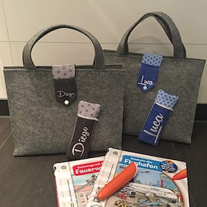 Könnte beinhalten: Zwei graue Filz-Tragetaschen mit personalisierten Sticknamen "Luca" und "Diego" auf der Vorderseite. Jede Tasche hat eine passende Stiftebox mit dem gleichen Namen und Sternenmuster.