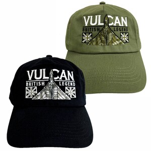 以下が含まれることがあります： 「Vulcan British Legend」という文字と、バルカン爆撃機の刺繍が施されたベースボールキャップが2つ。1つは黒、もう1つは緑です。