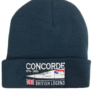 May include: A navy blue knit beanie with a white embroidered Concorde logo and the text "1976-2003" and "BRITISH LEGEND". The logo features a white silhouette of the Concorde supersonic jet with a red and blue stripe.