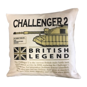 May include: A beige pillow with a black and white illustration of a tank with the text "CHALLENGER 2 BRITISH LEGEND" and a timeline of the UK Combat Timeline. The text below the image reads "The Challenger 2 is the current British main battle tank which entered service in 1998 replacing the Challenger 1. This tank has 2nd generation Chobham armour (classified), 120mm rifled gun and two 7.62mm chain guns as standard. There have been many upgrades and variants since 1998."