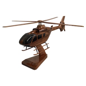May include: A wooden model of a brown helicopter with black accents. The helicopter is on a wooden stand.
