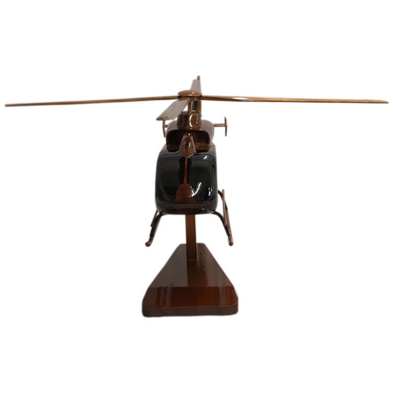 May include: A wooden model of a brown helicopter with black accents. The helicopter is on a wooden stand.