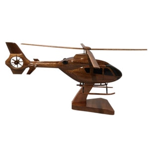 May include: A wooden model of a brown helicopter with a black cockpit and a wooden stand. The helicopter has a single rotor and a tail rotor.