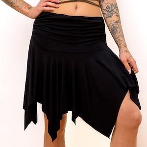 Può includere: Gonna asimmetrica nera con design drappeggiato. La gonna presenta una vita alta e un orlo a fazzoletto. Il tessuto sembra essere un materiale morbido e leggero, adatto per la danza o l'abbigliamento casual.