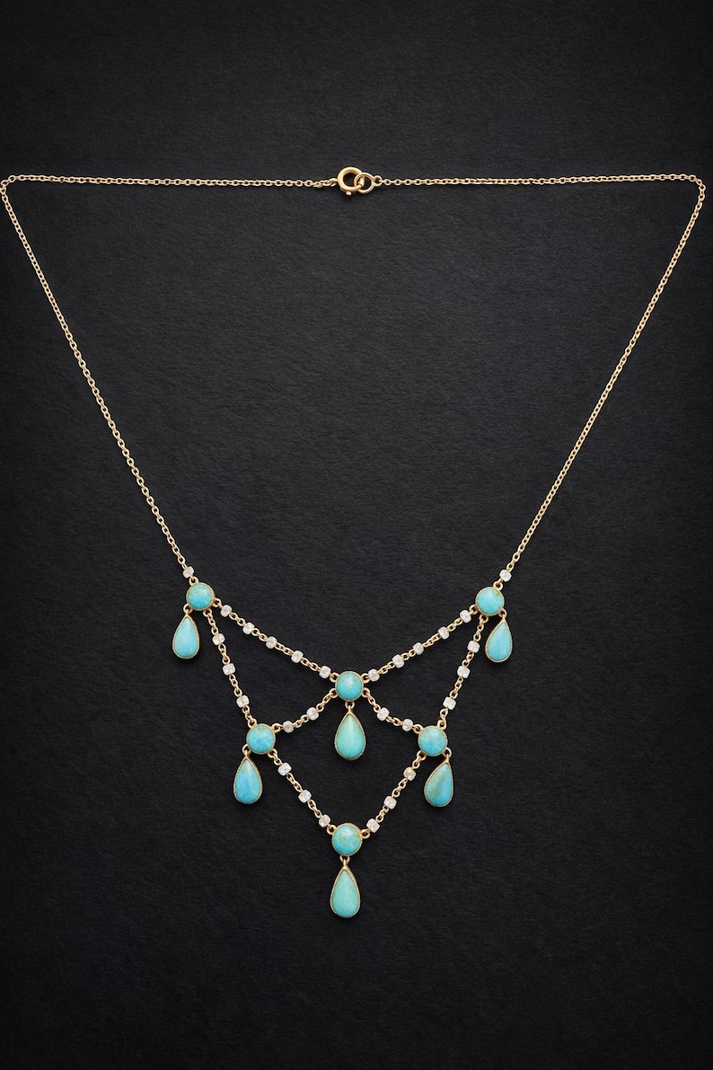 May include: A gold-toned necklace with a delicate chain design. The necklace features turquoise teardrop-shaped pendants and small white gemstones. The necklace is displayed against a black background.