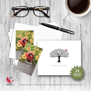 May include: A collection of stationery items, including note cards, insert cards, and envelopes. The image features a white card with a black tree design and a red bird, along with cards with a cardinal bird image. Also included are a pair of eyeglasses, a pen, and a cup of coffee.