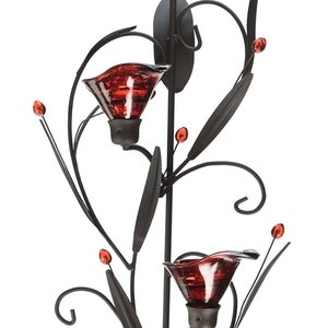 Può includere: Applique da parete in metallo nero con due portacandele in vetro rosso. L'applique è progettata a forma di fiore con delicati rotoli e foglie.