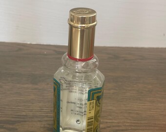 Puede incluir: Una botella de vidrio transparente con una tapa dorada y una etiqueta verde y dorada. La etiqueta tiene el texto "Crabtree & Evelyn" y "Classic Cologne". La botella está sobre una superficie de madera.