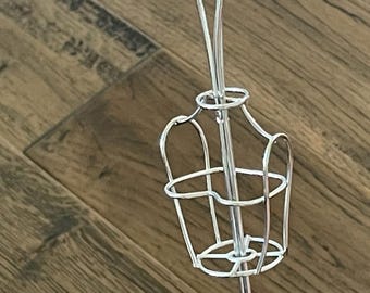 May include: Silver metal jewelry stand with three curved arms and a round base. The stand has a cage-like design in the middle.