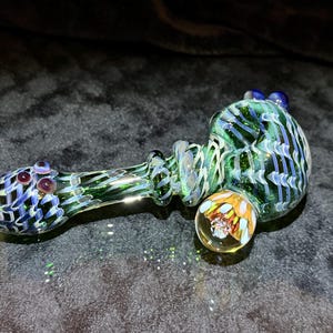 Large glass hand pipe in lush greens with ghostly purple wrap and rake exterior, deep purple accents and implosion marble with crushed opal