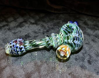 Large glass hand pipe in lush greens with ghostly purple wrap and rake exterior, deep purple accents and implosion marble with crushed opal