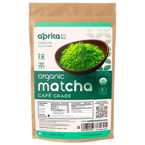 Puede incluir: Una bolsa de papel marr&oacute;n de t&eacute; matcha org&aacute;nico en polvo. La bolsa presenta una etiqueta verde y blanca con la marca "aprika" y las palabras "organic matcha caf&eacute; grade". Se muestra un cuenco de matcha verde brillante. La bolsa contiene 500g de matcha.