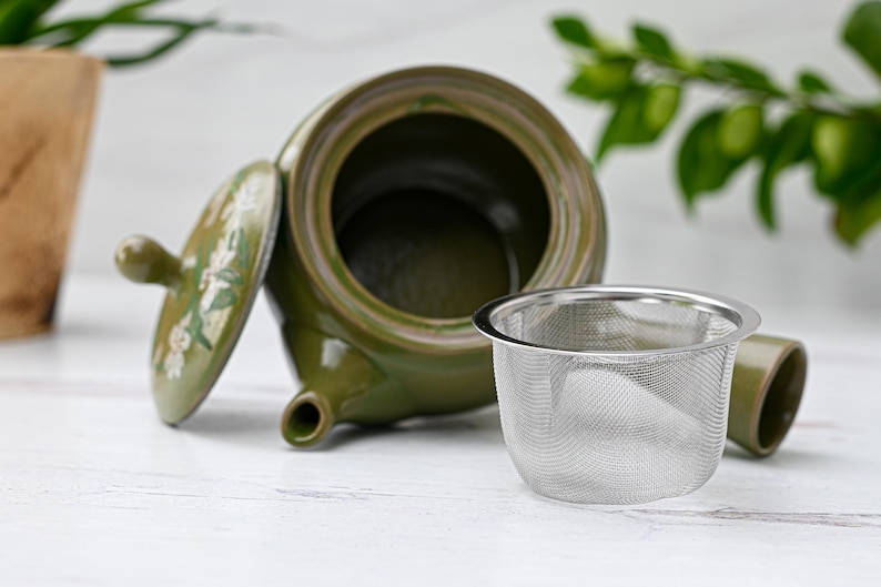 Puede incluir: Una tetera de cer&aacute;mica verde con un dise&ntilde;o floral y una tapa extra&iacute;ble. La tetera tiene un filtro integrado y un infusor de acero inoxidable a juego.