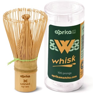 May include: A bamboo matcha whisk with 100 prongs in a clear plastic container. The container has a green label with the text "aprika whisk" and "aprikamatcha.com".