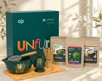 May include: A matcha tea set with a green ceramic bowl, whisk, and powder packets. The set includes a green box with the text "UNFUr" and "united by tea". The matcha powder packets are labeled "organic matcha" and "organic hojicha".