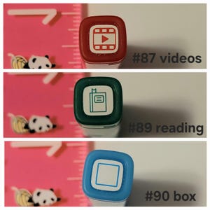 May include: Three red, green, and blue square-shaped stampers with different icons. The red stamper has a play button inside a film reel, the green stamper has a closed book with a bookmark, and the blue stamper has a square. The text below each stamper reads "#87 videos", "#89 reading", and "#90 box".