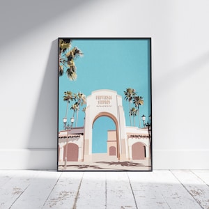 May include: A digital illustration of the Universal Studios Hollywood entrance archway with palm trees and a blue sky in the background.