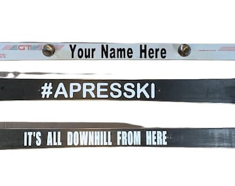 May include: Three white ski decals with black text. The top decal says "Your Name Here" with the Head brand logo on either side. The middle decal says "#APRESSKI". The bottom decal says "IT'S ALL DOWNHILL FROM HERE".