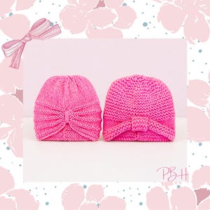 May include: Two bright pink knitted baby turbans. Each turban features a knotted detail at the front. The turbans are displayed on a white surface against a soft pink background with floral accents and a decorative bow.