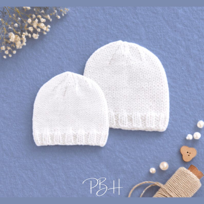 May include: Two white knitted beanies are shown on a blue surface. The beanies are of different sizes, with a smaller one in front and a larger one behind. The hats have a ribbed brim and a simple design. The image also includes decorative elements like pearls and a wooden button.