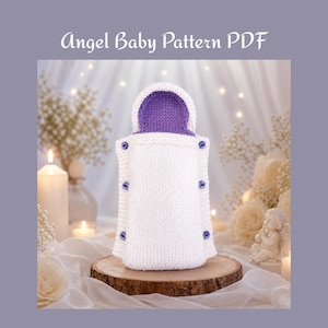 Könnte beinhalten: Ein weißer gestrickter Babyschlafsack mit einer violetten Innenkapuze und drei kleinen violetten Knöpfen auf jeder Seite. Der Text Angel Baby Pattern PDF steht oben im Bild. Der Artikel besteht aus einem strukturierten Strickstoff.