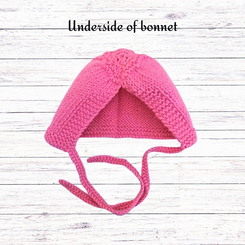Puede incluir: Un gorro tejido a mano de color rosa brillante con un patr&oacute;n de punto bobo texturizado y dos lazos largos tejidos para atar. El texto "Underside of bonnet" est&aacute; impreso en negro sobre la prenda, mostrando la construcci&oacute;n interior del art&iacute;culo.