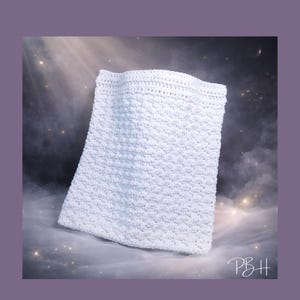 May include: A white, rectangular crocheted item with a textured surface. The item is made of a soft, fluffy material and has a slightly curved top edge. The background is a dark, starry sky.