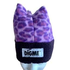 May include: Purple and pink leopard print fleece beanie with a black fleece band and a black logo that reads "DIGME™ JACKSON HOLE, WY."