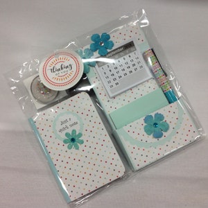 May include: A set of stationery supplies in a clear plastic bag. The set includes a small notepad with a polka dot pattern and the text "Just a quick note", a larger notepad with a calendar for September 2019, a pen with a colorful polka dot pattern, and a small round sticker with the text "thinking of you".