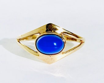 May include: A gold ring with a blue oval-shaped gemstone set in a diamond-shaped setting.