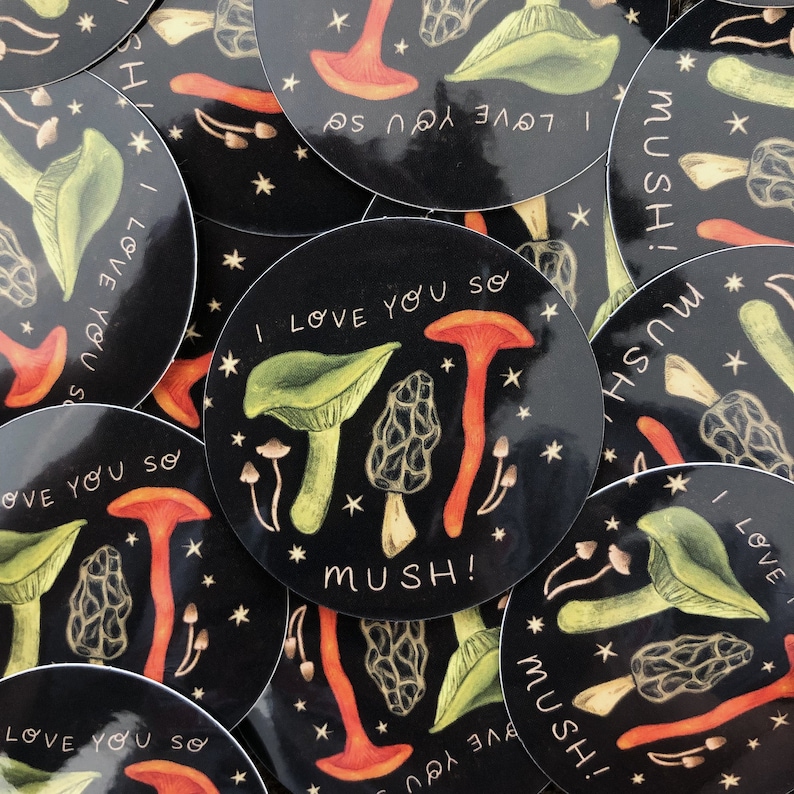 以下が含まれることがあります： 黒い背景に、キノコと「I love you so mush!」という白黒の文字が書かれたステッカーのセット。ステッカーは星やその他の小さなディテールで飾られています。