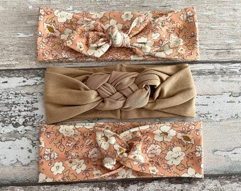 May include: Three headbands, one brown and two with a floral pattern in shades of pink and white.