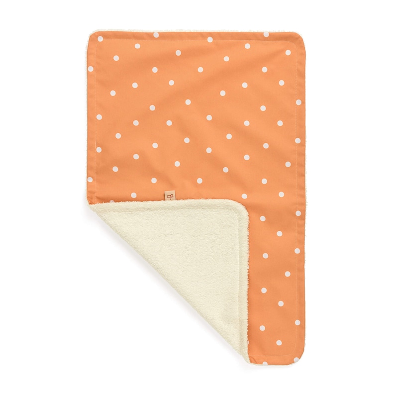 May include: A soft, orange and white polka dot baby blanket with a white sherpa lining.