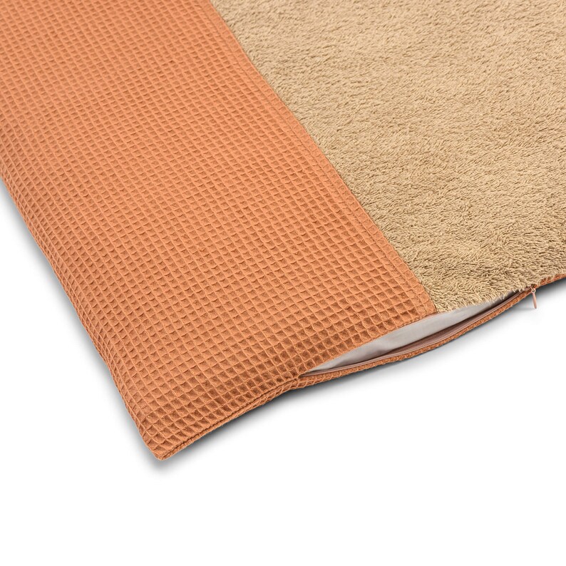 May include: A brown waffle-textured pillow with a tan fuzzy side. The pillow has a zipper closure.