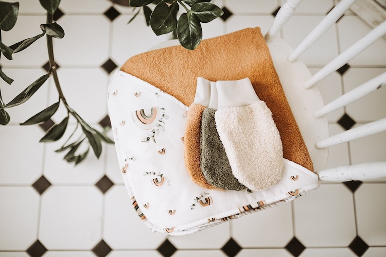 May include: A set of three hooded towels for babies, featuring a white background with a rainbow pattern. The towels are made of soft, absorbent material and are perfect for keeping little ones warm and dry after bath time.