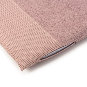 May include: A soft, blush-colored pillow with a waffle-textured side and a plush terrycloth side. The pillow has a zipper closure.